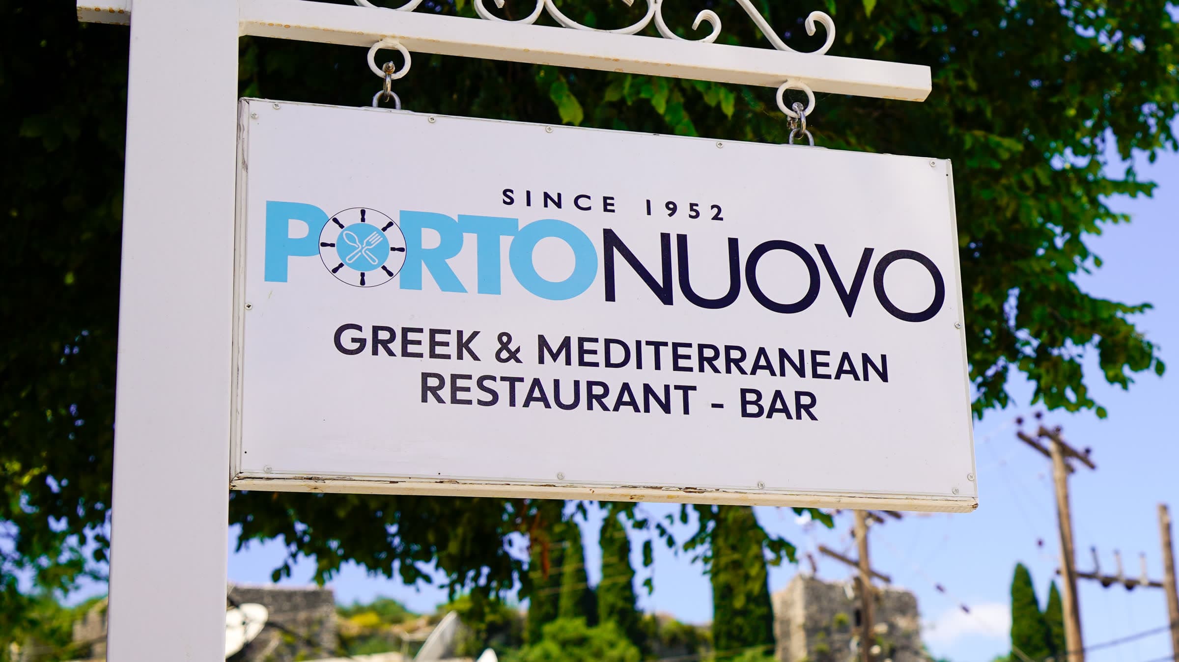The Porto Nuovo sign on Kassiopi harbour, Corfu — a fixture since 1952