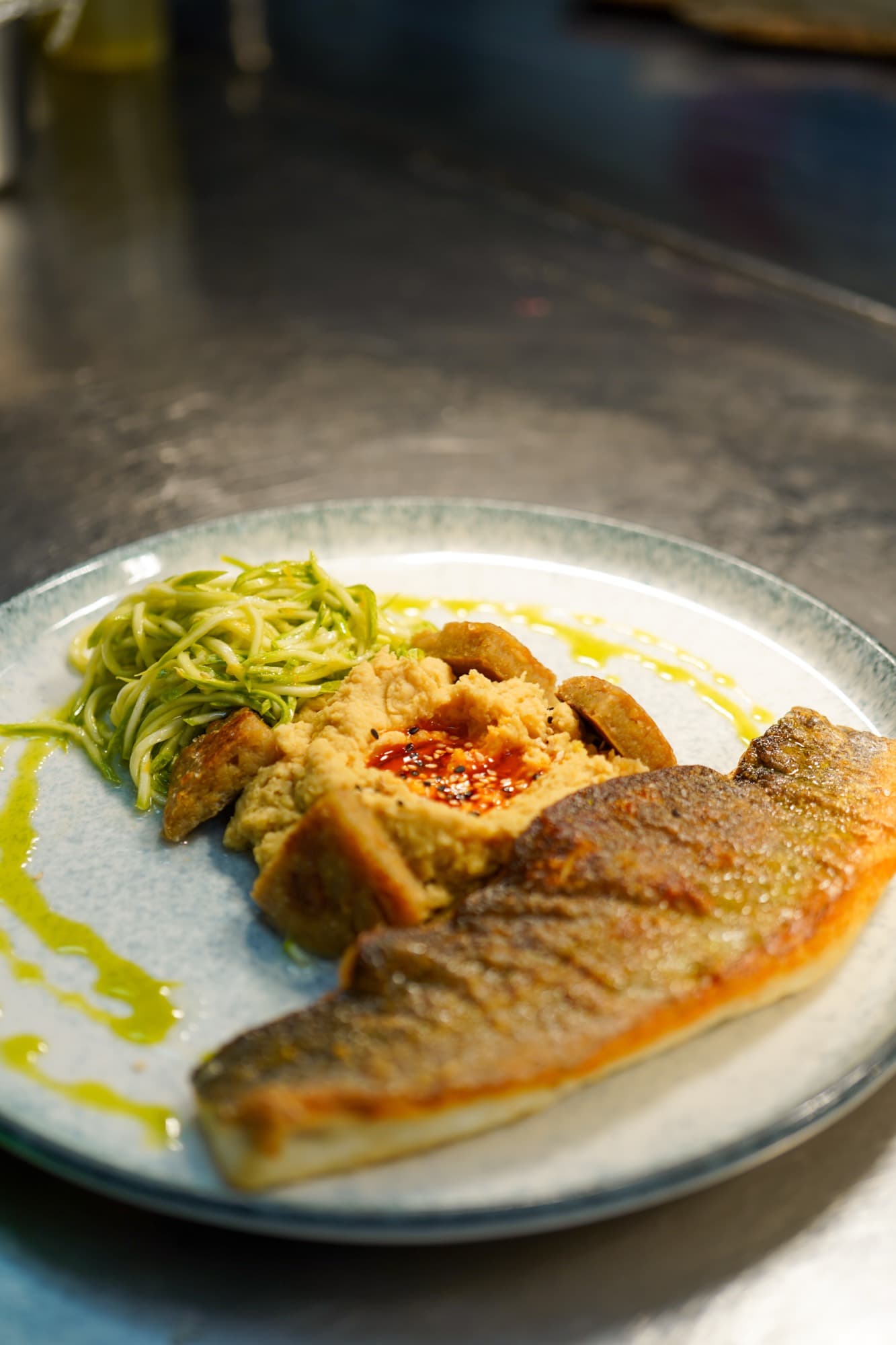 A plated fish of the day, dressed with greens